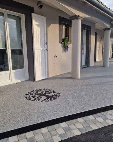 Terrasse extérieure en résine grise avec un motif décoratif d'arbre de vie noir, réalisée par CMG LYON