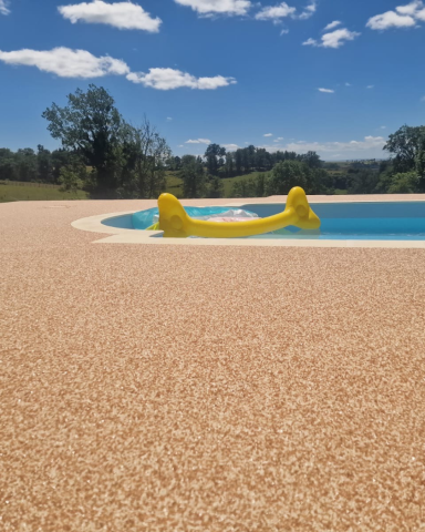 Plage de piscine recouverte d'un revêtement de sol en résine beige effet sable, réalisée par CMG LYON